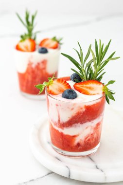 Lezzetli sağlıklı kahvaltı, çilekli smoothie ve doğal yoğurt ve yaban mersini ve biberiye.