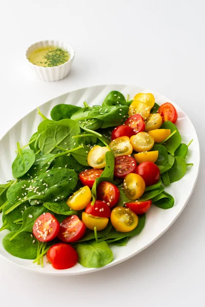 色拉与黄色和红色西红柿和菠菜 顶部看椭圆形盘与生菜在白色背景 — 图库照片