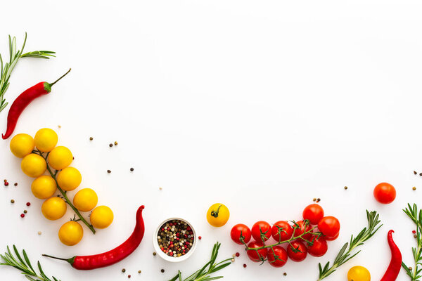 Yellow and red tomatoes, hot peppers, rosemary and spices on a white background, food background, top view, copy space