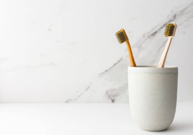 Seramik bardakta doğal kılları olan tahta diş fırçaları, doğal ağız hijyen ürünleri.
