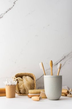 Seramik bardakta doğal tüyleri olan tahta diş fırçaları, yüz ve cilt bakım ürünleri, banyo aksesuarları, spa ve güzellik konsepti.