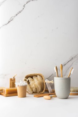 Seramik bardakta doğal tüyleri olan tahta diş fırçaları, yüz ve cilt bakım ürünleri, banyo aksesuarları, spa ve güzellik konsepti.