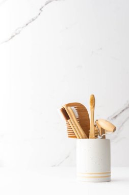 Seramik bardakta doğal tüyleri olan tahta diş fırçaları, yüz ve cilt bakım ürünleri, banyo aksesuarları, spa ve güzellik konsepti.