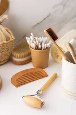 Seramik bardakta doğal tüyleri olan tahta diş fırçaları, yüz ve cilt bakım ürünleri, banyo aksesuarları, spa ve güzellik konsepti.