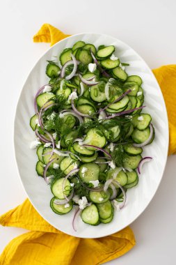 Beyaz oval tabakta salatalık, soğan ve peynir salatası.