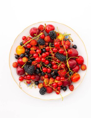 Beyaz arka planda taze meyveler, kırmızı ve siyah üzümler ve siyah dutlar, yabani çilekler ve kirazlar, üst manzara.