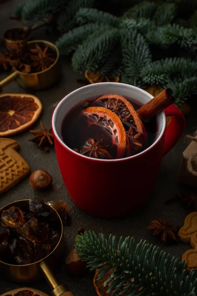 圣诞热酒精饮料在云杉枝间的一个装有柑橘 香味香料和肉桂的杯子里 覆盖着葡萄酒 — 图库照片