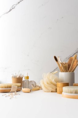 Seramik bardakta doğal tüyleri olan tahta diş fırçaları, yüz ve cilt bakım ürünleri, banyo aksesuarları, spa ve güzellik konsepti.