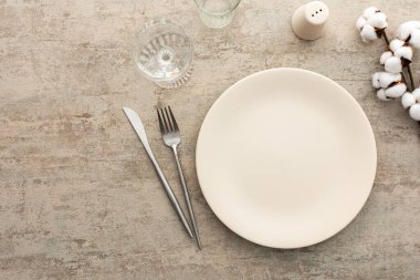 Kahverengi arkaplanda masa, tabak ve çatal bıçak seti, kuru çiçeklerle süslenmiş servis tablosunun üst görüntüsü