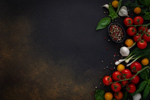 Gıda arka planı, taze kırmızı ve sarı domatesler, baharatlar ve fesleğen yaprakları, koyu arkaplanda sarımsak ve yeşil soğan, sağlıklı gıda konsepti, fotokopi alanı, üst görünüm