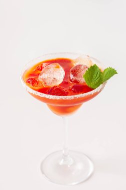 Alcoholic drink with tomato juice in a glass with ice close-up on a white background
