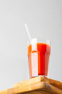 Bottom view of homemade freshly squeezed tomato juice with a glass straw close-up