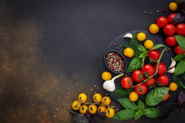 Yiyecek arka planı, taze kırmızı ve sarı domatesler, baharatlar ve fesleğen yaprakları, sarımsak ve yeşil soğanlar koyu tahtada, sağlıklı gıda konsepti, fotokopi alanı, üst görünüm