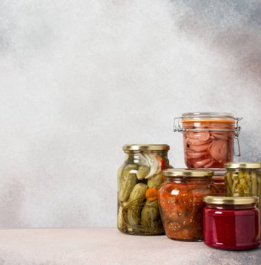 Preserving vegetables for the winter, canned vegetables in jars on a light background, pickled or fermented vegetables, copy space