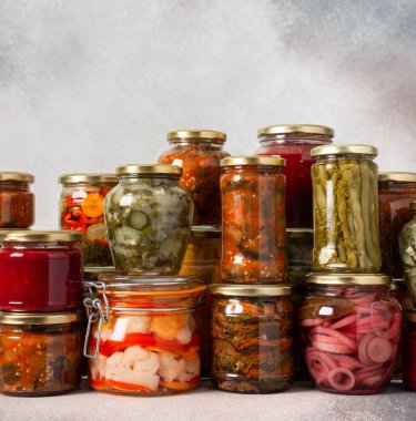 Preserving vegetables for the winter, canned vegetables in jars on a light background, pickled or fermented vegetables, copy space