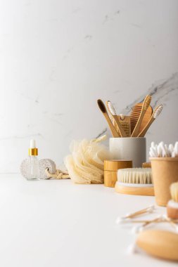 Seramik bardakta doğal tüyleri olan tahta diş fırçaları, yüz ve cilt bakım ürünleri, banyo aksesuarları, spa ve güzellik konsepti.