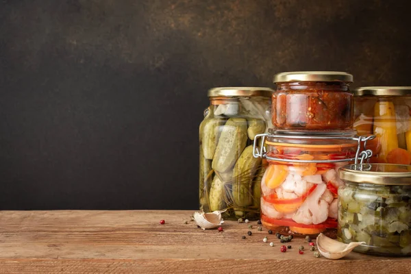 Preserving vegetables for the winter, canned vegetables in jars on a wooden table against a brown wall, pickled or fermented vegetables, copy space