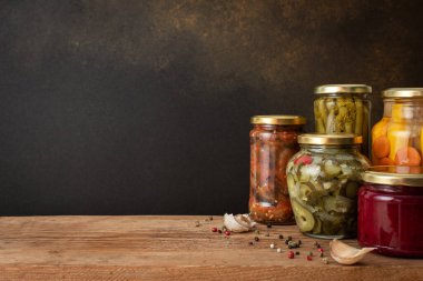 Preserving vegetables for the winter, canned vegetables in jars on a wooden table against a brown wall, pickled or fermented vegetables, copy space