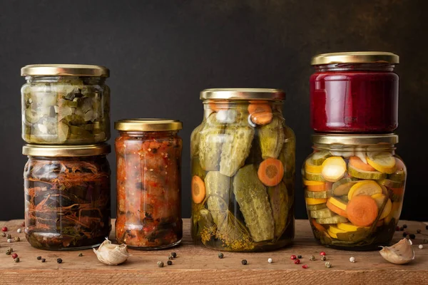 Preserving vegetables for the winter, canned vegetables in jars on a wooden table against a brown wall, pickled or fermented vegetables, copy space