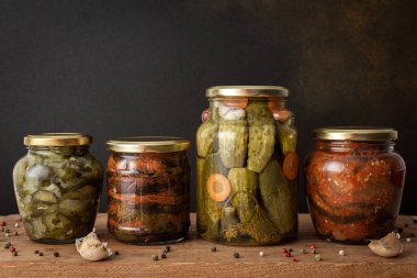 Preserving vegetables for the winter, canned vegetables in jars on a wooden table against a brown wall, pickled or fermented vegetables, copy space