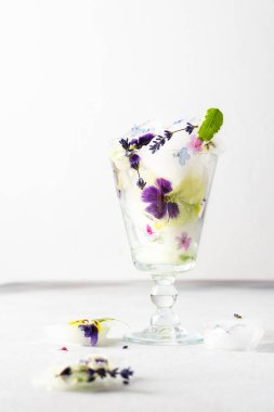 Refreshing cold drink with frozen flowers, colorful pansies and lavender and Verbena