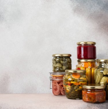 Preserving vegetables for the winter, canned vegetables in jars on a light background, pickled or fermented vegetables, copy space