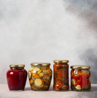 Preserving vegetables for the winter, canned vegetables in jars on a light background, pickled or fermented vegetables, copy space