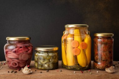 Preserving vegetables for the winter, canned vegetables in jars on a wooden table against a brown wall, pickled or fermented vegetables, copy space