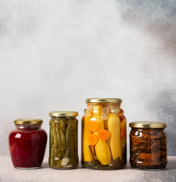 Preserving vegetables for the winter, canned vegetables in jars on a light background, pickled or fermented vegetables, copy space