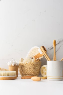 Seramik bardakta doğal tüyleri olan tahta diş fırçaları, yüz ve cilt bakım ürünleri, banyo aksesuarları, spa ve güzellik konsepti.