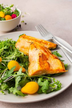 Delicious lunch with salad and fried char, healthy red fish and microgreens with cherry tomatoes, top view, copy space