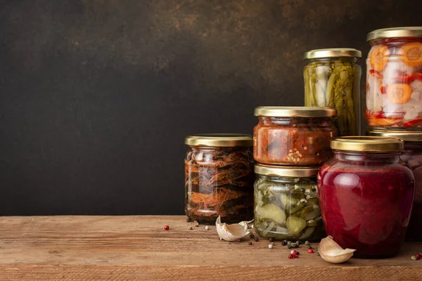 Preserving vegetables for the winter, canned vegetables in jars on a wooden table against a brown wall, pickled or fermented vegetables, copy space