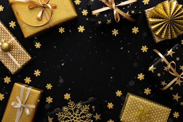 Golden and black gift boxes with bows and snowflakes and snow on a black background, Merry Christmas and Happy New Year