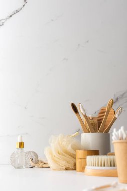 Seramik bardakta doğal tüyleri olan tahta diş fırçaları, yüz ve cilt bakım ürünleri, banyo aksesuarları, spa ve güzellik konsepti.