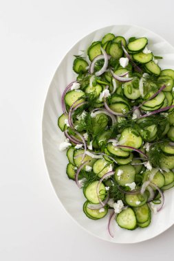 Beyaz oval tabakta salatalık, soğan ve peynir salatası.