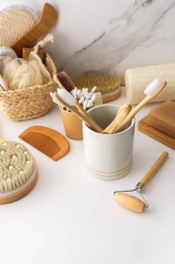 Seramik bardakta doğal tüyleri olan tahta diş fırçaları, yüz ve cilt bakım ürünleri, banyo aksesuarları, spa ve güzellik konsepti.