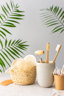Seramik bardakta doğal tüyleri olan tahta diş fırçaları, yüz ve cilt bakım ürünleri, banyo aksesuarları, spa ve güzellik konsepti.