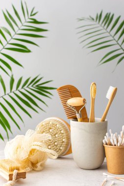 Seramik bardakta doğal tüyleri olan tahta diş fırçaları, yüz ve cilt bakım ürünleri, banyo aksesuarları, spa ve güzellik konsepti.