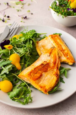 Delicious lunch with salad and fried char, healthy red fish and microgreens with cherry tomatoes, top view, copy space