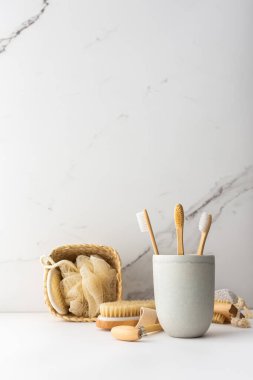 Seramik bardakta doğal tüyleri olan tahta diş fırçaları, yüz ve cilt bakım ürünleri, banyo aksesuarları, spa ve güzellik konsepti.