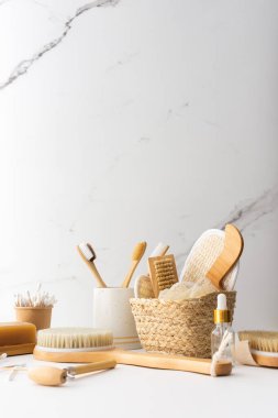 Seramik bardakta doğal tüyleri olan tahta diş fırçaları, yüz ve cilt bakım ürünleri, banyo aksesuarları, spa ve güzellik konsepti.