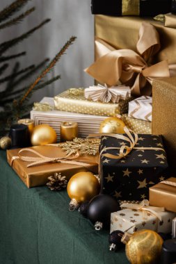 Tatil hazırlıkları, Noel ağacını giydirmek, siyah ve altın hediyeler ve Noel oyuncakları ve köknar ağacının yanındaki masanın üzerindeki süslemeler.