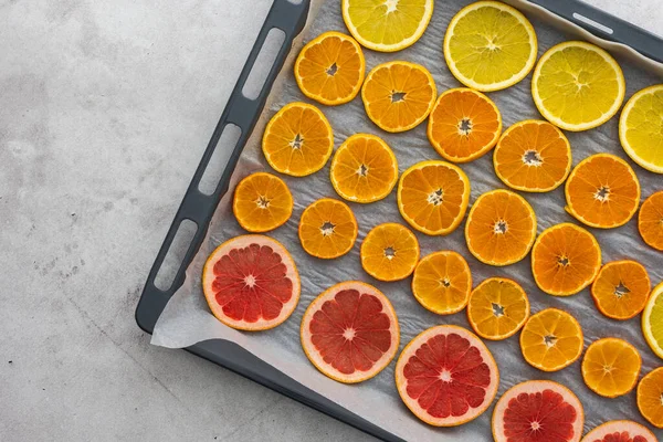 Sliced orange, tangerine and grapefruit slices on baking sheet, preparing citrus wedges for Christmas garland