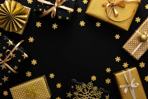 Golden and black gift boxes with bows and snowflakes and snow on a black background, Merry Christmas and Happy New Year