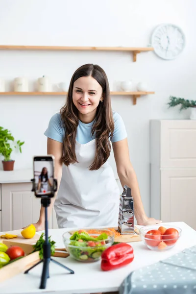 Lächelnde Köchin Weißer Schürze Die Neben Einem Tisch Steht Dem lizenzfreie Stockfotos