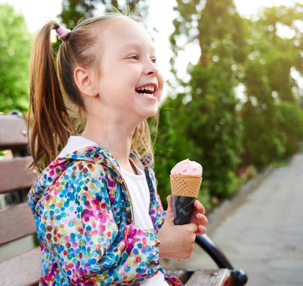 在户外的长椅上坐着一个笑容满面的小女孩 她带着乳酪蛋卷里的冰淇淋 假期和夏季时间概念 — 图库照片