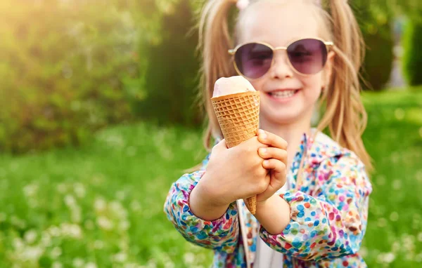 特写镜头冰淇淋在一个华夫饼锥中手拿着 喜形于色的孩子把它放在夏日绿色草坪的背景上 假日和夏季时间概念 — 图库照片