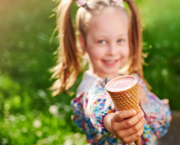 在华夫饼蛋筒里放着雪糕的特写手 喜形于色的孩子把它放在夏日绿色草坪的背景上 假日和夏季时间概念 — 图库照片