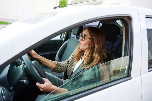 Korkak iş kadını ön vagona bakıyor. Arabasını kullanan kadın sürücü, yan görüş.