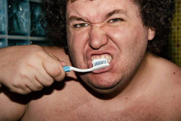 Funny fat man shaves in the bathroom.